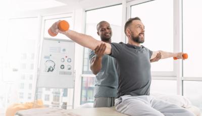 Therapist helping a patient lift weights